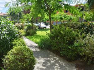 un jardin avec un trottoir, des arbres et des buissons dans l'établissement Au cœur du village d' Argelès-sur-Mer, à Argelès-sur-Mer