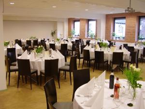 un salón de banquetes con mesas y sillas blancas en ALCATRAZ Hotel am Japanischen Garten, en Kaiserslautern