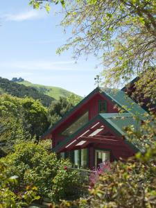 une maison rouge avec un toit vert dans l'établissement Hereweka Garden Retreat, à Dunedin