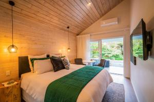 a bedroom with a large bed with a wooden ceiling at Wairua Lodge - Rainforest River Retreat in Whitianga