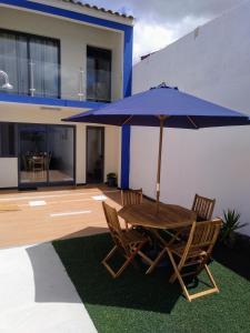 a wooden table and chairs with a blue umbrella at Casa do Califórnia in Ribeira Grande