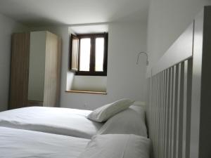 1 dormitorio con 2 camas blancas y espejo en Casona 1828, en Cabuérniga