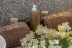 a bottle of soap sitting next to towels and flowers at The Puncak Lombok in Senggigi