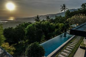 a house with a swimming pool and a view of the forest at The Puncak Lombok in Senggigi