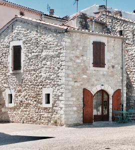 ein altes Steingebäude mit einer Holztür und einem Gebäude in der Unterkunft Ruoms Petite Maison 3* centre-village in Ruoms