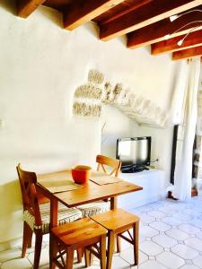 a wooden table and chairs in a room with a tv at Ruoms Petite Maison 3* centre-village in Ruoms