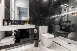 a black bathroom with a toilet and a sink at Franklin38 in Auckland