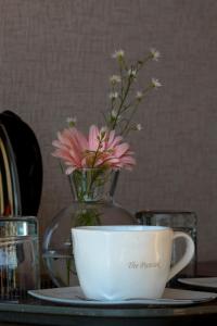 a cup and a vase with flowers on a table at The Puncak Lombok in Senggigi