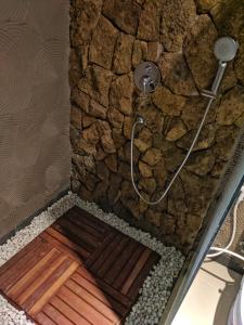 a shower in a bathroom with a stone wall at Surawan Bisma Ubud in Ubud