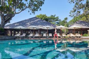 a woman standing in front of a swimming pool at Hyatt Regency Bali in Sanur