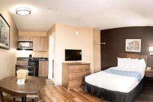 a small hotel room with a bed and a kitchen at Suburban Studios Charlotte-Ballantyne in Charlotte