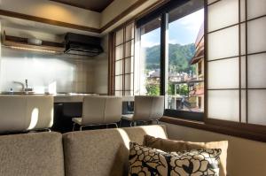 a living room with a couch and some windows at Tanuki Nozawa in Nozawa Onsen