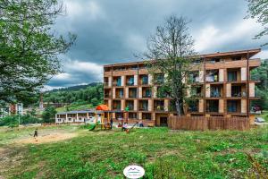 um grande edifício com um parque infantil em frente em InkInn Bakuriani The Valley em Bakuriani