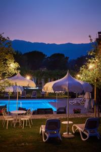 a pool with chairs and umbrellas at night at Hotel Villaguarda Prosecco Area in Follina