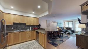 a kitchen with wooden cabinets and a living room at Powderhorn by Whistler Blackcomb Vacation Rentals in Whistler