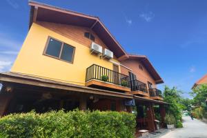 a yellow building with windows and balconies on a street at La Luna Italian Restaurant & Accommodation in Ko Lipe