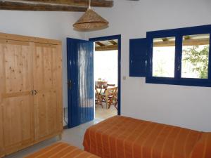 1 dormitorio con puertas azules, 1 cama y 1 mesa en Camping Bungalows Armalygal, en Murillo de Gállego