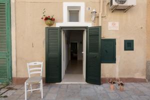 una entrada a un edificio con puertas verdes y una silla en Dimora del Murattiano, en Monopoli