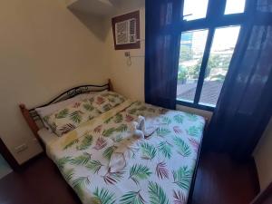 a small bedroom with a bed with a tropical print at Azalea Place Robinsons Residences Cebu in Cebu City +34 photos