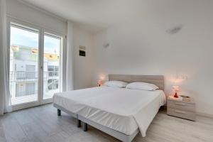 a white bedroom with a bed and a large window at Venice Golf residence in Venice-Lido