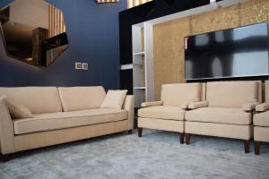 a living room with two couches and a flat screen tv at Durrat Manzli ApartHotel in Al Khobar