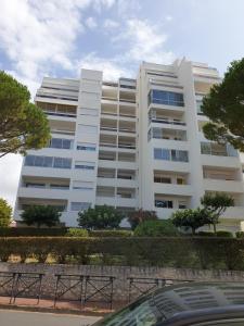 un gran edificio blanco con árboles delante de él en Le P'tit Benèze, en Royan