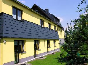 ein gelbes Gebäude mit schwarzem Dach in der Unterkunft Pension Am Zechengrund in Kurort Oberwiesenthal