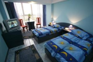 a hotel room with two beds and a television at Hotel Grim in Craiova