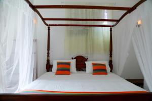 a canopy bed with colorful pillows in a bedroom at Nisala Guest in Galle