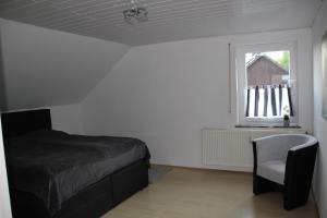 a bedroom with a bed and a chair and a window at Ferienwohnung Abersfelder mit Balkon in Wildflecken