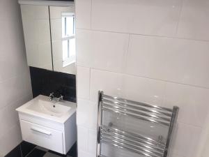a white bathroom with a sink and a mirror at 143 New Road Porthcawl in Porthcawl