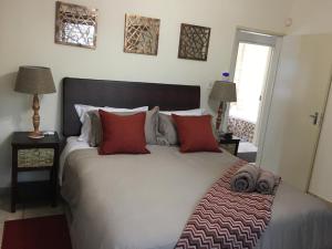 um quarto com uma grande cama branca com almofadas vermelhas em Villa Danamara em Phalaborwa