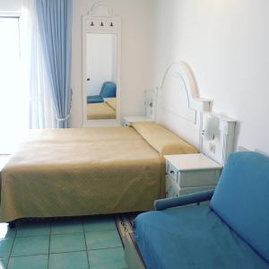 a bedroom with two beds and a mirror and a chair at Hotel Isolabella in Ventotene