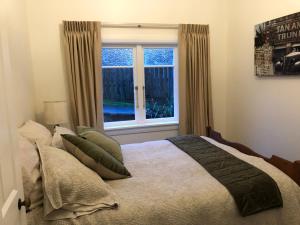 1 dormitorio con cama y ventana en Araluen Cottage, en Waihi