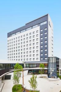 a large white building with a bridge in front of it at Hotel Lumiere Grande Nagareyama-Otakanomori in Nagareyama