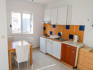 a kitchen with white cabinets and a table and a window at Luka 3 in Podgora +5 photos