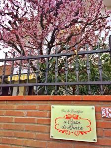 un cartel en una valla con flores rosas en A Casa di Laura en Occhiobello