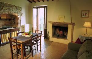 sala de estar con mesa, sillas y chimenea en La Casa Di Piandelbello, en San Venanzo