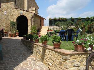 un mur en pierre avec des plantes en pot, des tables et des chaises dans l'établissement Borghetto Di San Filippo, à Barberino di Val dʼElsa