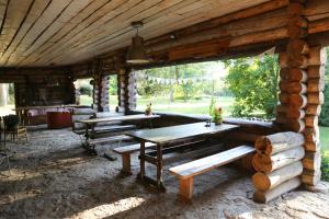 a porch of a log cabin with wooden tables and benches at Annenhof Holiday House in Pudisoo