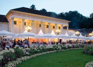 un grupo de personas sentadas en mesas bajo sombrillas blancas en City Apartment an der Caracalla Therme, en Baden-Baden