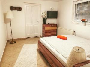 a bedroom with a bed with an orange pillow on it at Tassi Halászcsárda-Harcsa ház in Tass