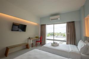 um quarto de hotel com duas camas e uma janela em โรงแรมโกลว์ รัตนา เพลส em Songkhla