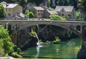 a bridge over a river with people in canoes at La maison d'Arnal in Sainte-Énimie