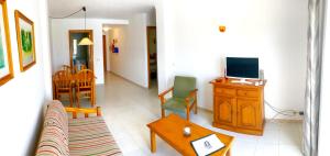 a living room with a couch and a tv at Apartaments Marina Sol i Pins in Cala Figuera