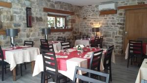 a dining room with tables and chairs and a stone wall at LA PETITE MAISON D'ARNAL in Sainte-Énimie