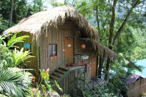 a small tree house with a staircase and a thatch roof at Green Hill Hostel & Tour in Ha Giang