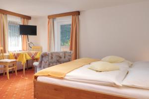 um quarto com uma cama, uma cadeira e uma janela em Landhaus Hinteregger em Bad Kleinkirchheim