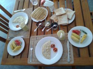 a wooden table with plates of breakfast food on it at Hotel Gayan's in Udawalawe +34 photos