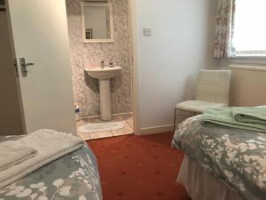 um quarto com 2 camas, um lavatório e uma casa de banho em The Clan Macfarlane Apartment em Kilmarnock